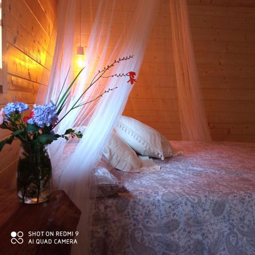 a vase of flowers on a bed with a curtain at Belaustegi turismo rural in Ispáster