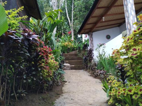 a path leading to a house with flowers and plants at Puri Sunset Homestay in Munduk
