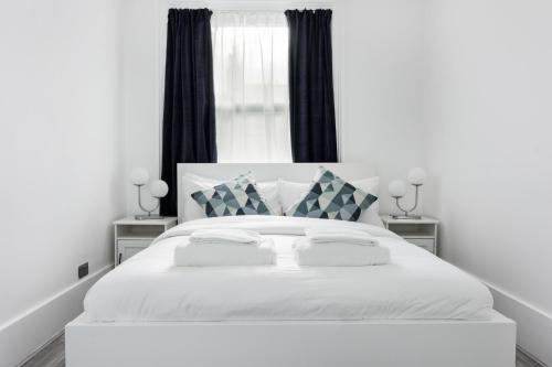 1 cama blanca con 2 almohadas y ventana en Luxury 3 Bedroom Apartment in Marylebone, en Londres