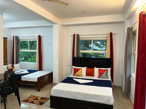 a bedroom with two beds and a table and two windows at Himadri munnar holidays in Munnar