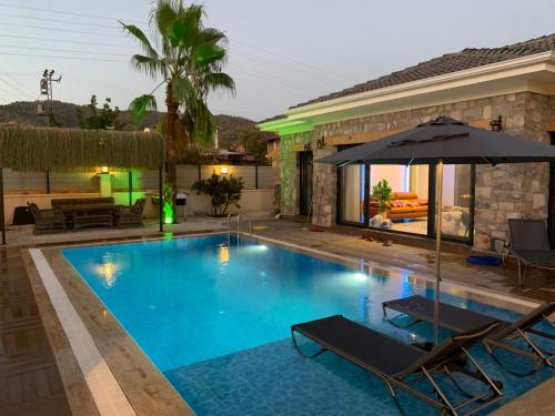 a swimming pool with two chairs and an umbrella at Müstakil havuzlu jakuzili tatil villası in Fethiye