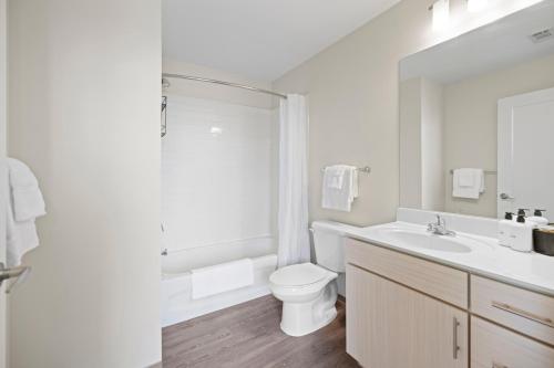 a white bathroom with a toilet and a sink at Placemakr Premier SoBro in Nashville