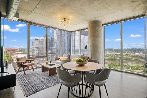 a living room with a table and chairs and large windows at Placemakr Premier SoBro in Nashville