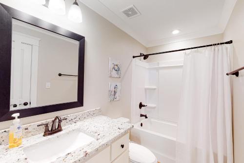 a bathroom with a sink and a toilet and a mirror at Beach Cottage East in Dauphin Island