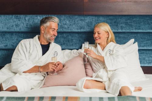 a man and woman sitting on a bed with drinks at Llanerch Vineyard Hotel in Hensol