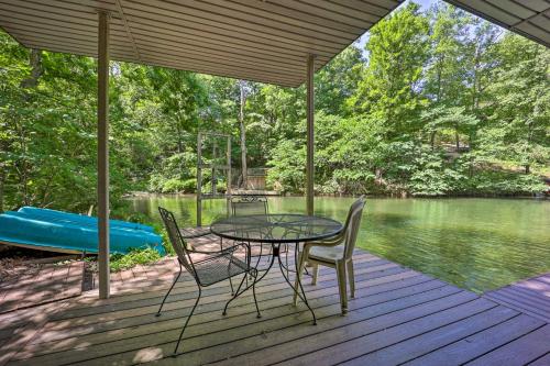a table and chairs sitting on a deck next to a lake at Lakefront Getaway with Private Dock and Kayaks! in Bella Vista