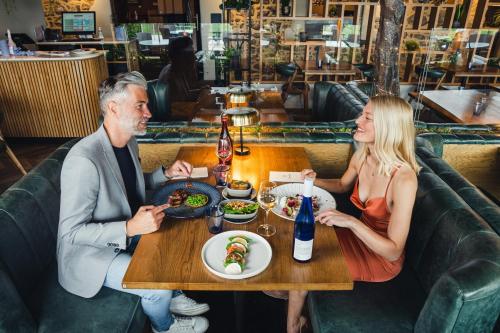 a man and woman sitting at a table in a restaurant at Llanerch Vineyard Hotel in Hensol