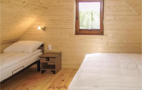 two beds in a wooden room with a window at Stunning Home In Gaski With Kitchen in Gąski