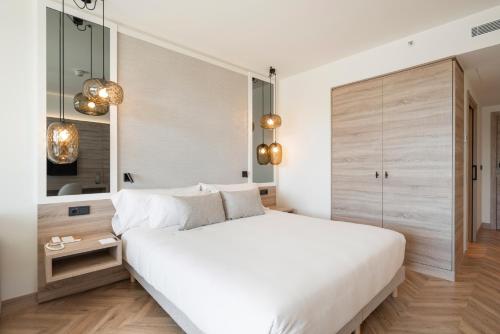 a bedroom with a large white bed and a mirror at Attica21 Vigo 4 Superior in Vigo