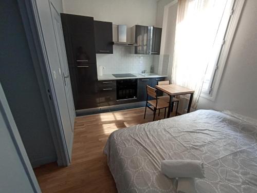 a bedroom with a bed and a kitchen with a table at Studio cosy - Hypercentre - 20 min to Paris in Maisons-Laffitte