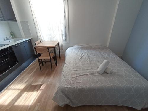 a bedroom with a bed and a kitchen and a table at Studio cosy - Hypercentre - 20 min to Paris in Maisons-Laffitte
