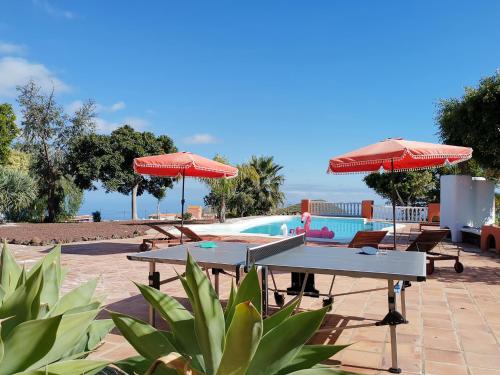 un patio con mesas y sombrillas y una piscina en KARAT Hacienda Miranda, en Charco del Pino