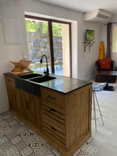 a kitchen with a sink and a large window at Hôtel Lou Caleù restaurant le Rocher des Abeilles in Saint-Martin-de-Castillon