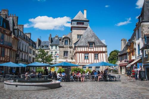 un grupo de personas sentadas en mesas y sombrillas en una calle de la ciudad en Quimper: T3 avec vue cathédrale proche gare, en Quimper