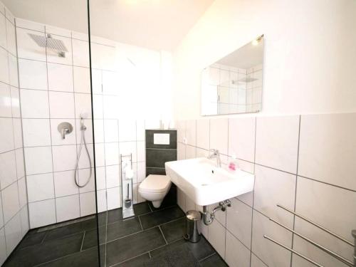 W łazience znajduje się umywalka, toaleta i lustro. w obiekcie Cozy holiday apartment on a farm in North Rhine Westphalia w mieście Jüchen