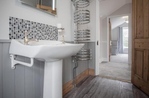 baño con lavabo blanco y pasillo en Pendeilo Villa - 5 Bedroom Holiday Home - Amroth, en Amroth