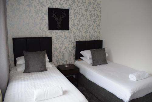 two beds sitting next to each other in a room at Kelpies Serviced Apartments- McLaughlan in Falkirk