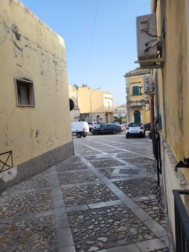 an alley with a building and cars parked on a street at La Perla Di Noto in Noto