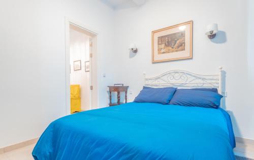 niebieskie łóżko w białej sypialni z niebieską narzutą w obiekcie Blue Waves Apartment with Maltese Balcony w mieście Valletta