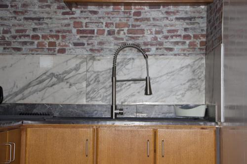 a kitchen with a sink and a brick wall at ROS’APPART in Yaoundé