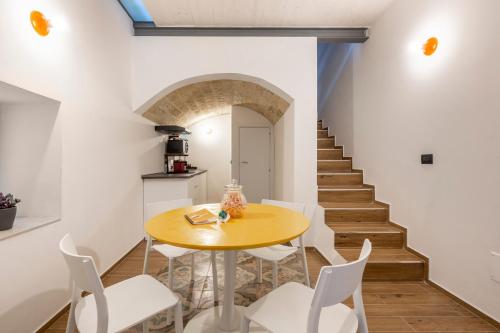 een eetkamer met een gele tafel en witte stoelen bij Just Here apartments - Lascia Fare a Dio in Bari