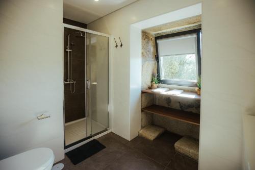 a bathroom with a shower and a toilet and a window at Casa da Vila - Pool & Hot Tub with Mountain View in Gerês in Terras de Bouro