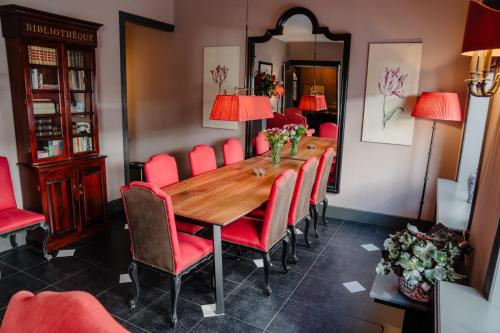a dining room with a wooden table and red chairs at Paleis Hotel in The Hague