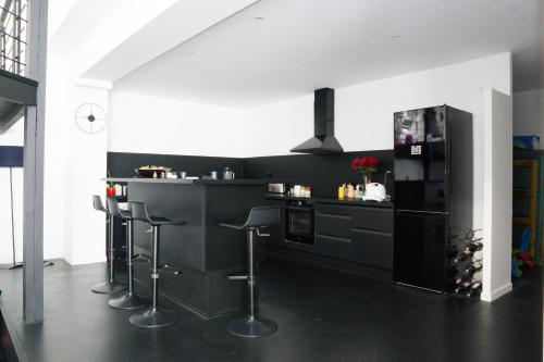 une cuisine avec un comptoir noir et des tabourets de bar dans l'établissement EXIGEHOME-Magnifique Loft à 15 minutes de Paris, à La Garenne-Colombes