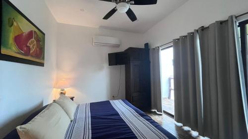a bedroom with a bed with a ceiling fan and a window at Aventura Pacifico Boutique Suites & Villas in Bucerías