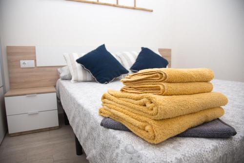 una pila de toallas sentadas encima de una cama en La Casita del Pescador en Caleta De Velez