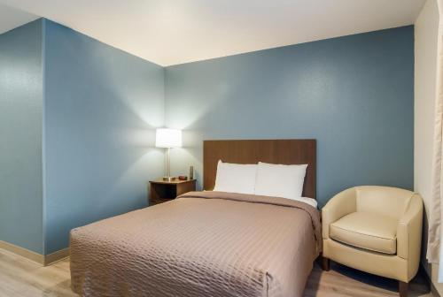 a bedroom with a bed and a chair at WoodSpring Suites Greensboro - High Point North in Greensboro