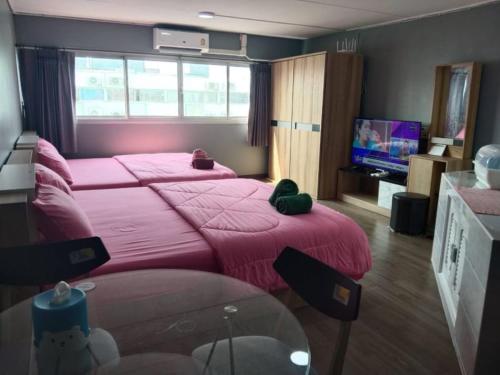 um quarto com 2 camas com lençóis cor-de-rosa e uma televisão em K.NAT Room service em Nonthaburi