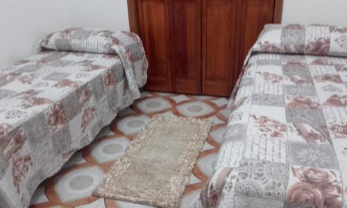 a bedroom with two beds and a rug on the floor at Casa Vacanza Di Maggio in Cinisi