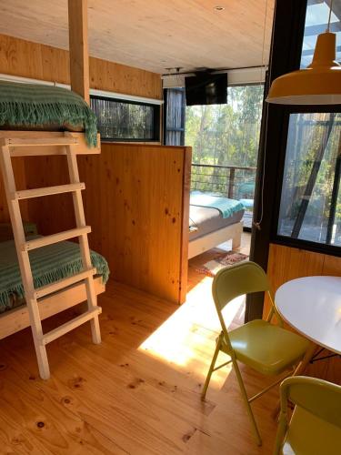 a room with a bunk bed and a table and a chair at Lodge KARKÚ in Pichilemu