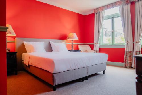 a red bedroom with a bed and a window at Paleis Hotel in The Hague