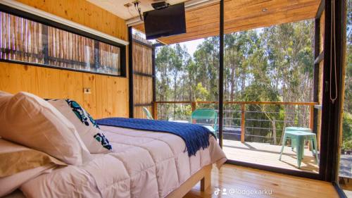 a bedroom with a bed and a large glass window at Lodge KARKÚ in Pichilemu