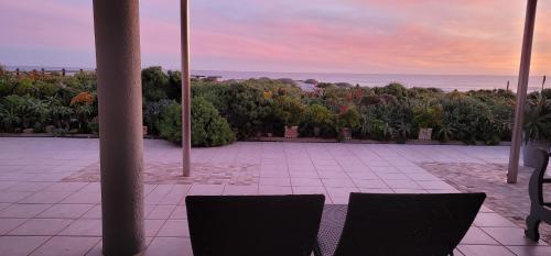 a patio with two chairs and a view of the ocean at On The Beach Apartments in Yzerfontein