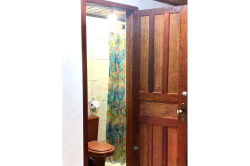 een badkamer met een toilet en een houten deur bij Chalé jeito de roça na Pedra Selada in Visconde De Maua
