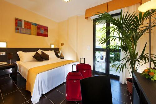 a hotel room with a bed and two suitcases at Park Hotel Kursaal in Misano Adriatico