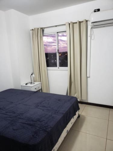 a bedroom with a blue bed and a window at Departamento Augusta in Posadas