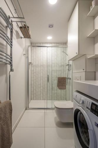 a bathroom with a shower and a washing machine at Amber Family Home Juodkrantė in Juodkrantė