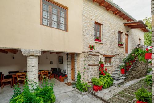 un edificio de piedra con un patio con mesas y sillas en Archontiko Rapti Stone Traditional House, en Monodendri