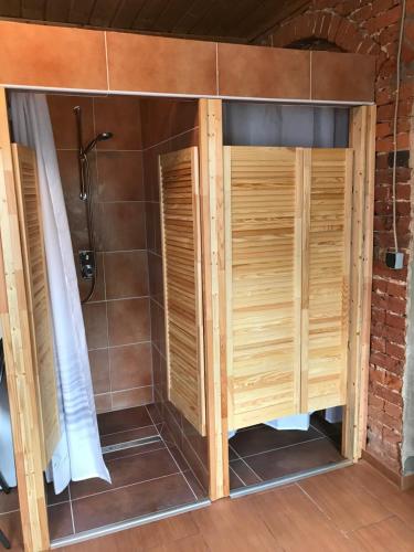 a shower stall with wooden doors in a bathroom at Hostel Meissen Old Town Bridge in Meißen