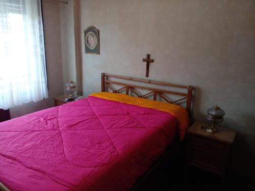 a bedroom with a pink bed with a cross on the wall at depto a 50 m del casino y plaza principal "se aceptan mascotas" in Termas de Río Hondo
