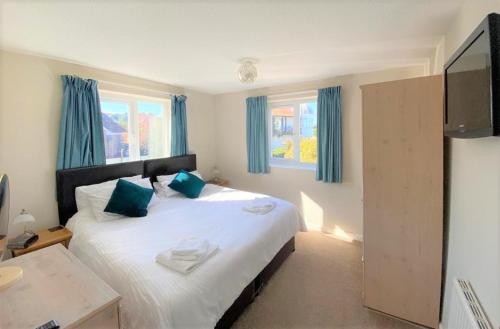 een slaapkamer met een groot wit bed met blauwe kussens bij Cliff Court Apartments in Torquay