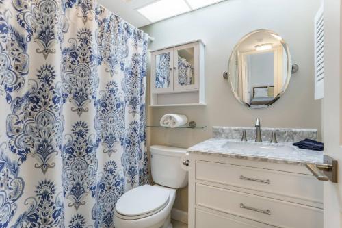 a bathroom with a toilet and a sink and a mirror at The Shore Club at Park Shore in Naples