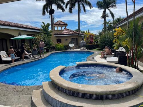 a swimming pool in a yard with people sitting around it at Las Brisas Resort and Villas in Jacó