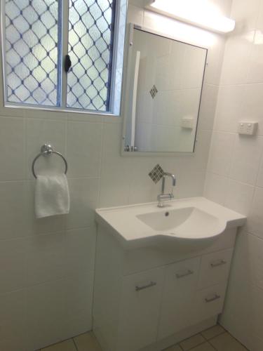 a white bathroom with a sink and a mirror at Country Road Motel in Charters Towers