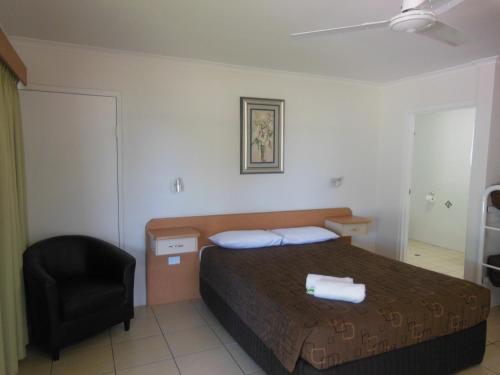 a bedroom with a bed and a black chair at Country Road Motel in Charters Towers