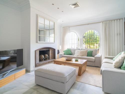 a living room with white furniture and a fireplace at Gorgeous townhouse with shared pool in the middle of Marbella All yours in Marbella